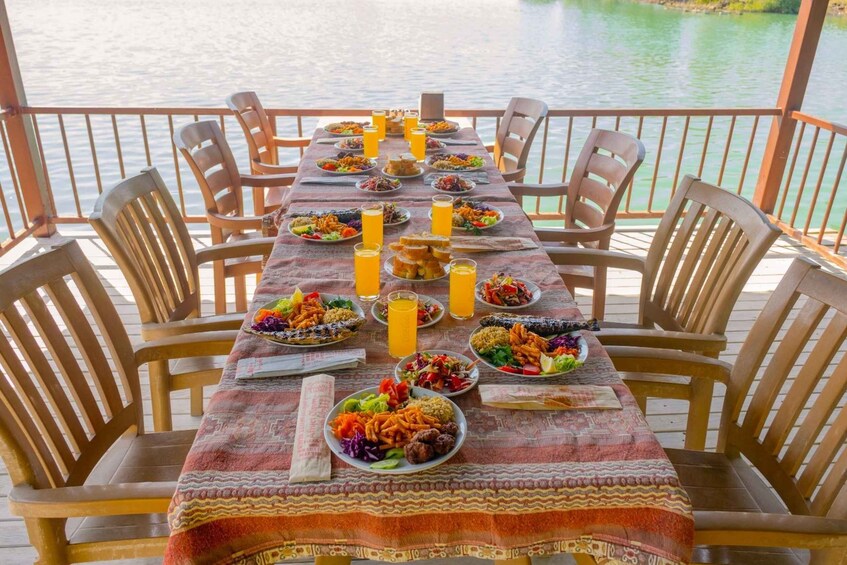 A table set for a meal with various dishes and drinks, overlooking a body of water. 5