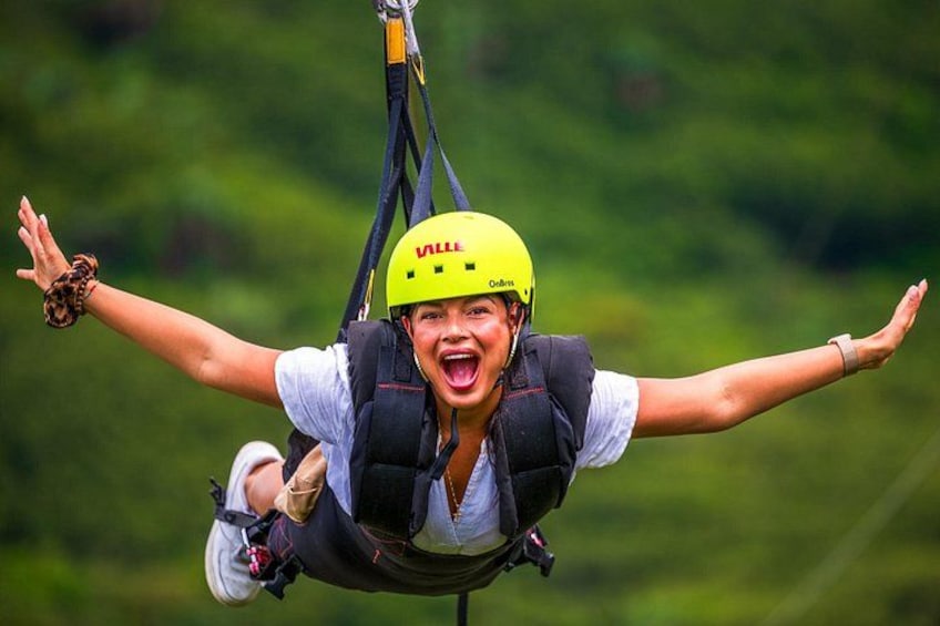 Une personne portant un casque jaune et un harnais de sécurité, suspendue en l’air, est probablement en train de pratiquer une activité de plein air, comme la tyrolienne ou le saut à l’élastique. 2