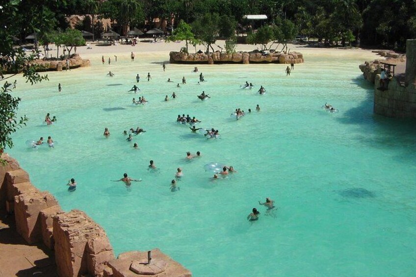 Una gran piscina al aire libre con gente nadando y tomando el sol. 5