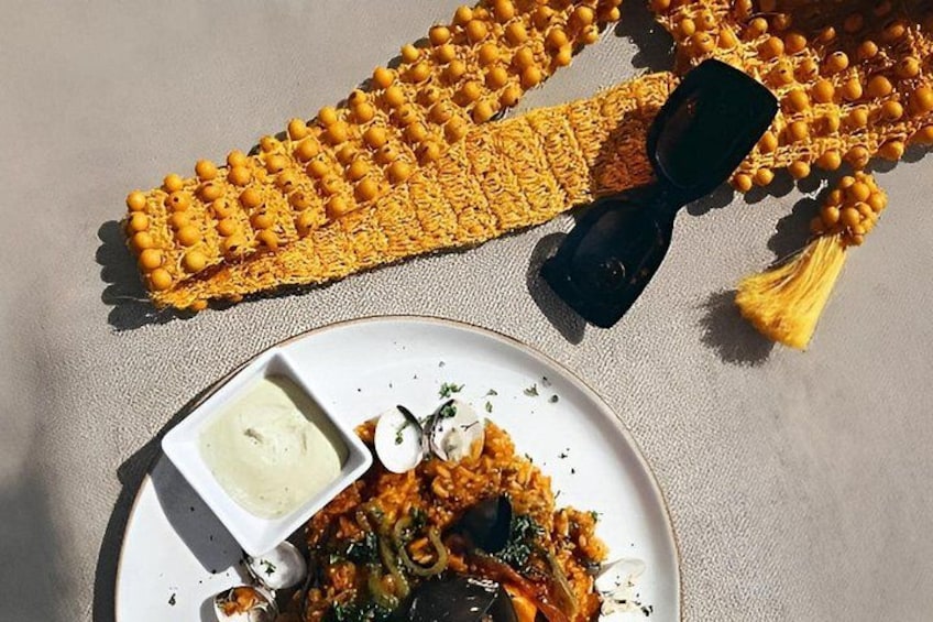 A plate of food with a side of sauce, a yellow woven item, and a black object. 5