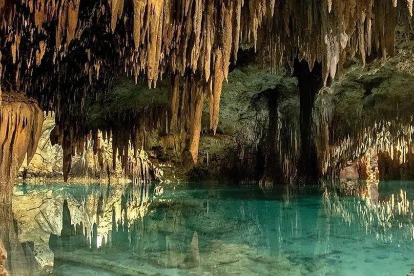 Una grotta con stalattiti e stalagmiti, uno specchio d'acqua e l'ingresso della grotta. 1