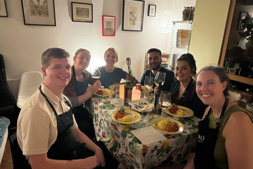 A group of people dining at a table with plates of food, wine glasses, and a bottle of wine. 2