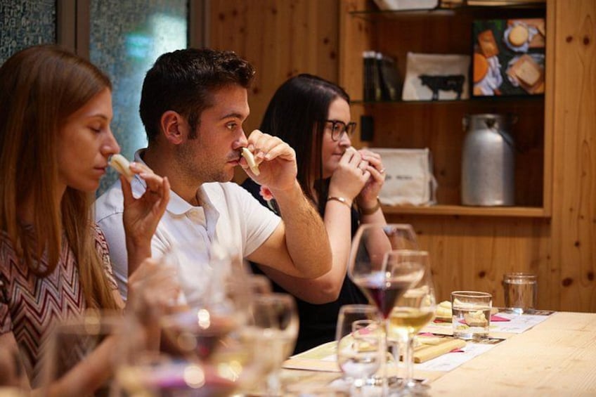 Personas sentadas a una mesa con copas de vino, un menú y una estantería de madera al fondo. 1