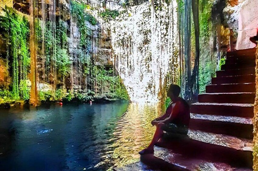 Una persona seduta su una scala accanto a una cascata. 3
