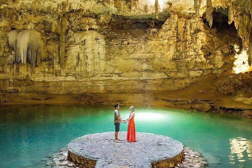Una coppia in piedi su una piattaforma circolare in pietra, all'interno di una grotta con una pozza d'acqua. 1