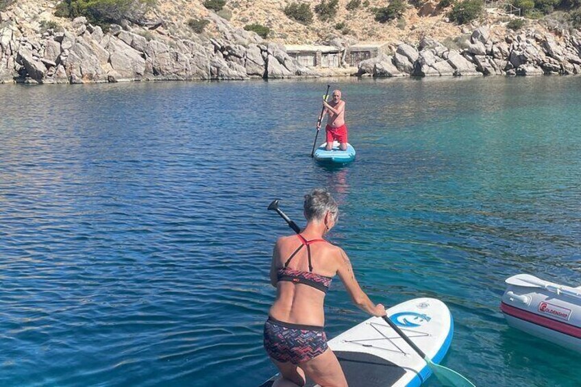 Two people paddleboarding on calm water with rocky shorelines in the background. 5