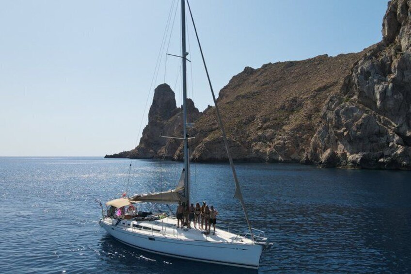 A sailboat with passengers near a rocky coastline. 3