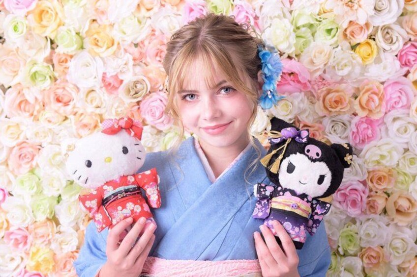 Iemand houdt pluche Hello Kitty speeltjes vast voor een achtergrond van kleurrijke bloemen. 4