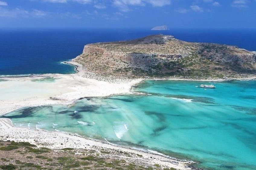 A coastal landscape with a sandy beach, turquoise waters, and a rocky hill. 5