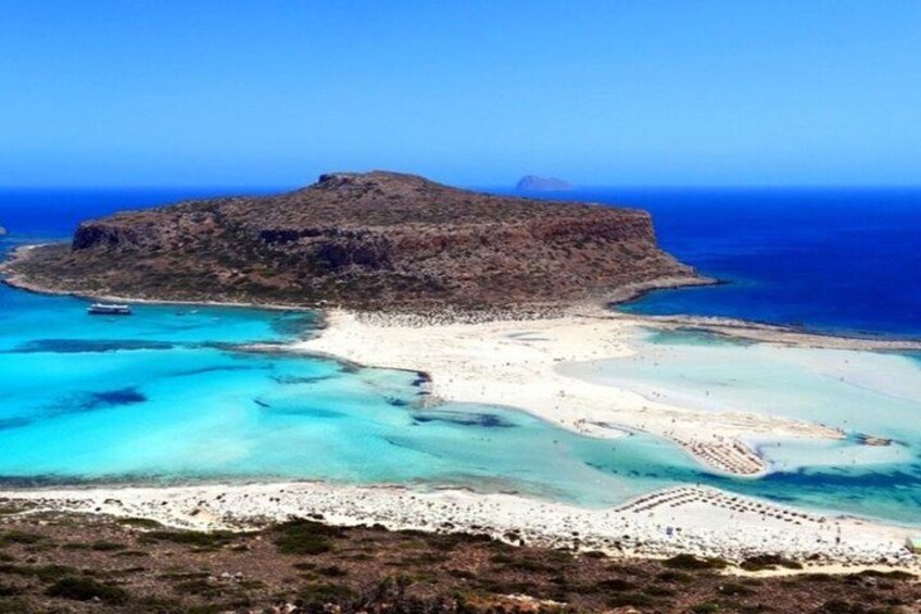 A coastal landscape with a rocky island, clear turquoise waters, and a sandy beach. 1