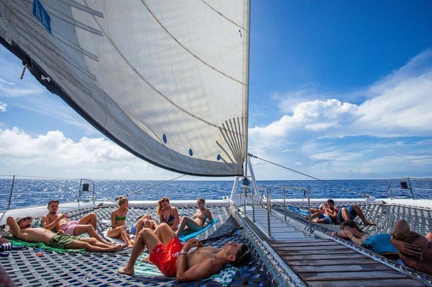 People relaxing on a boat deck with a sail. 3