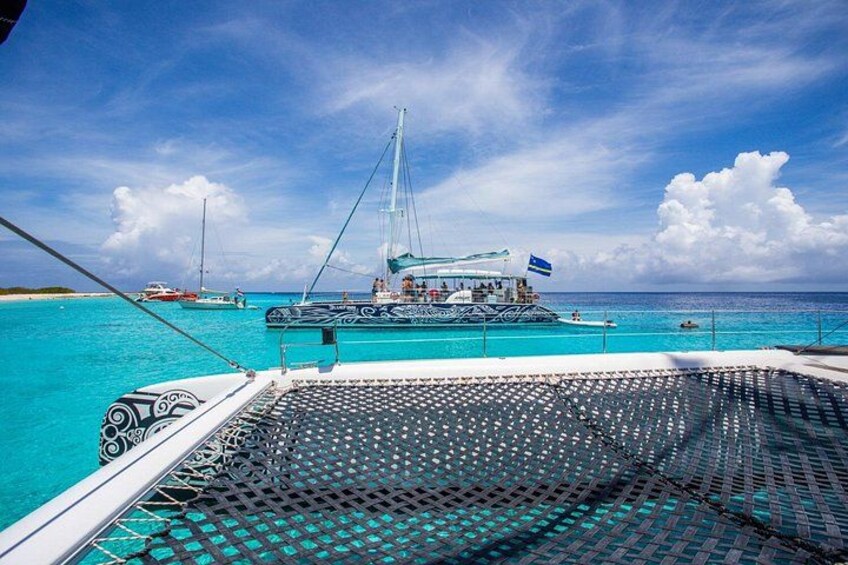 A boat with a blue flag, turquoise water, and a clear sky. 2