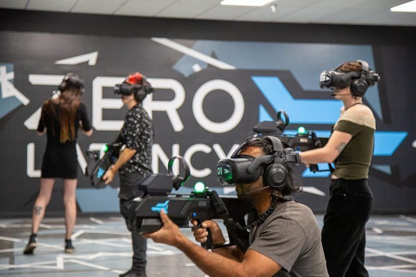 Personas usando gafas de realidad virtual en una habitación con un letrero que dice 'ZERO LATENCY'. 4