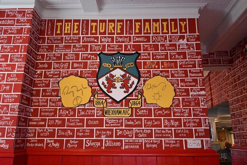 A wall with names and dates, a crest, and the text 'THE TURF FAMILY'. 4