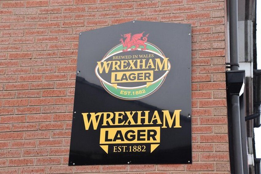 A sign for Wrexham Lager on a brick wall. 3