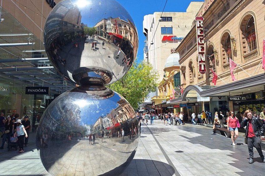 A reflective sculpture, a shopping area, and historic buildings. 3