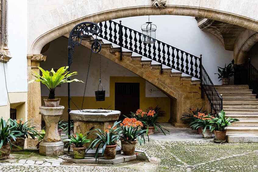 A courtyard with a stone staircase, potted plants, and a fountain. 3