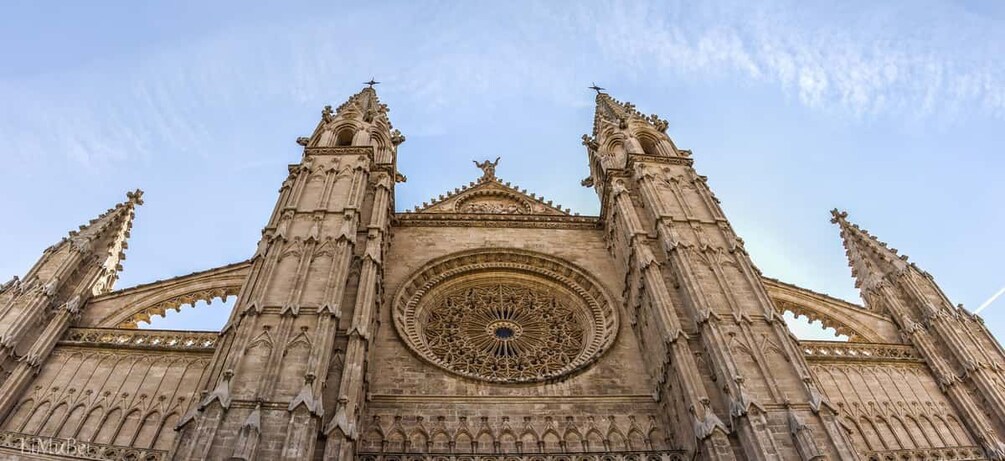 A Gothic cathedral with intricate stonework, a large circular stained glass window, and two tall spires. 2