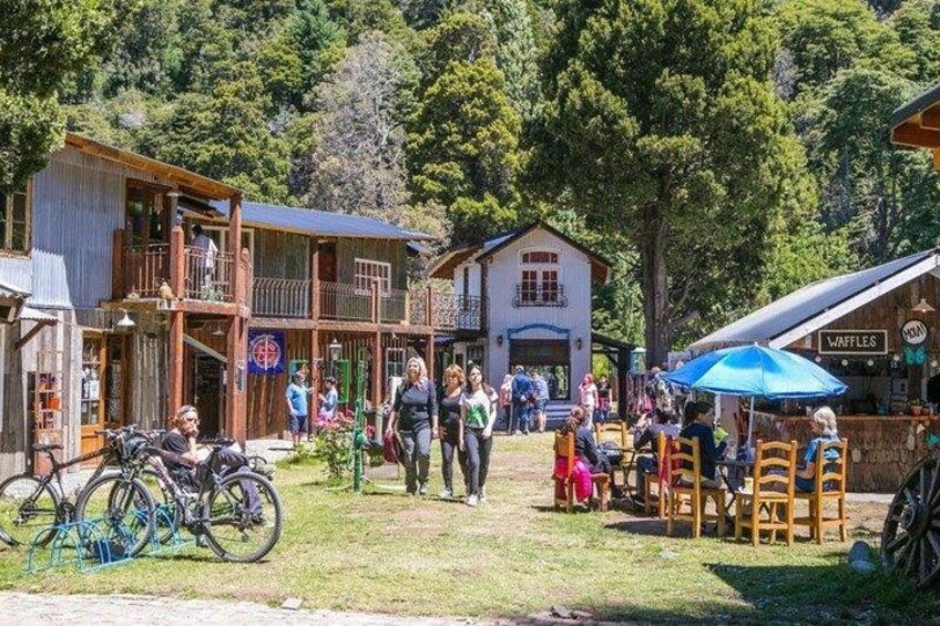 Un mercado al aire libre rústico con edificios de madera, bicicletas y gente caminando. 4