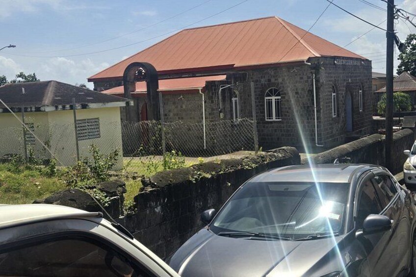 Un edificio con techo rojo, pared de piedra y un coche estacionado al frente. 2