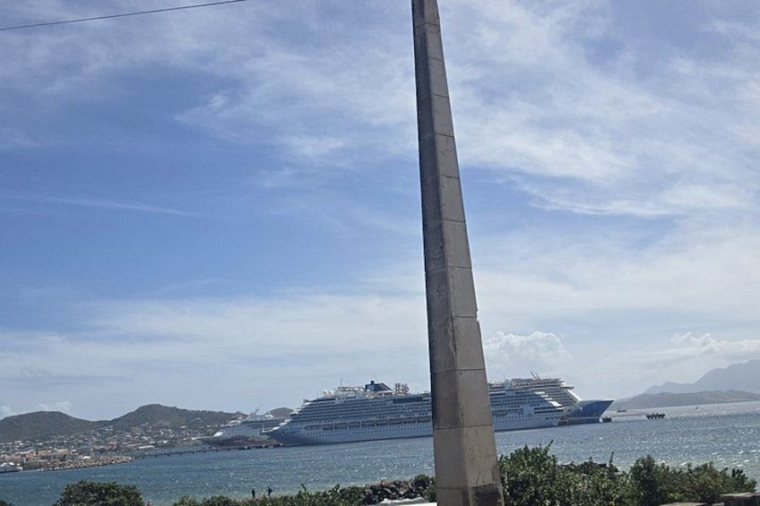 Un gran crucero amarrado en un puerto, con cielo despejado y montañas a lo lejos. 5