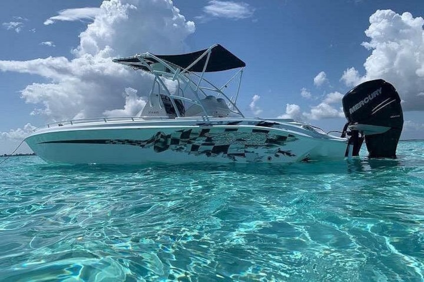 A white boat with a Mercury outboard motor on clear turquoise water. 1