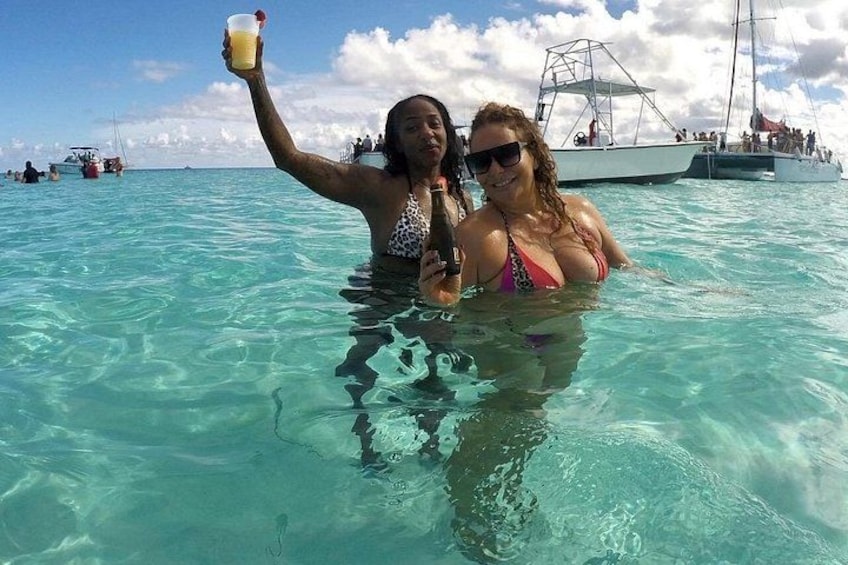 Two people in a clear blue sea, one holding a drink. 5