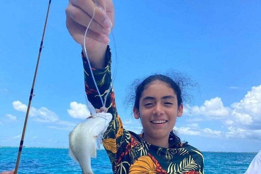 A person holding a fish on a boat with a clear blue sky and ocean in the background. 4
