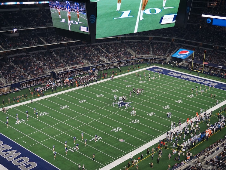 A football stadium with a large crowd, a football field, and a scoreboard. 2