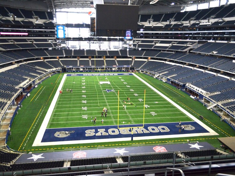A large stadium with a football field, seating areas, and a scoreboard. 4