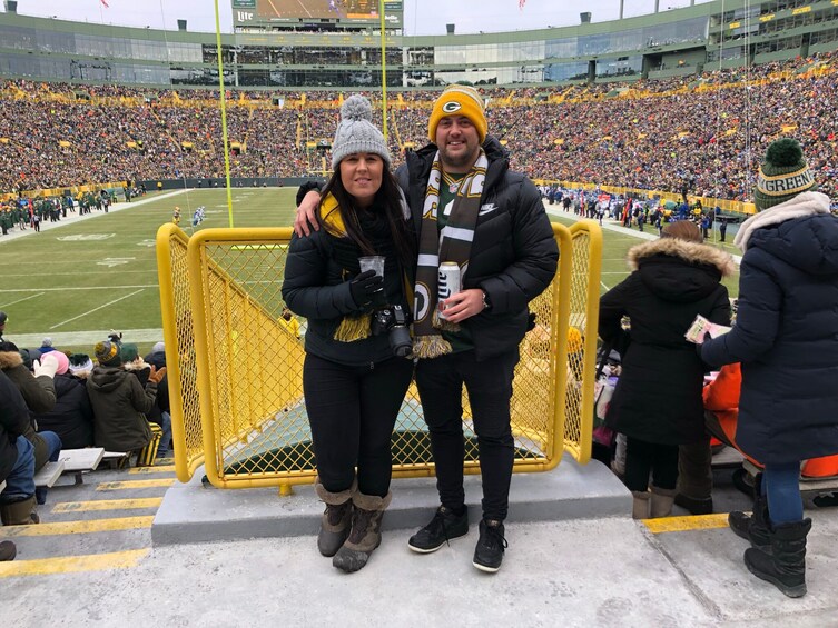 A stadium with a football game in progress, spectators in the stands, and a person holding a trophy. 2