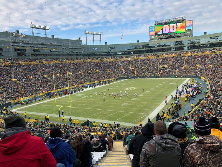 A football stadium filled with spectators, a football field, and a scoreboard. 1