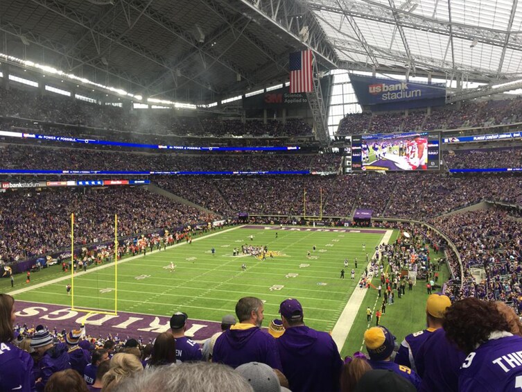 Ein Fußballstadion voller Zuschauer, eine große Anzeigetafel und ein Schild mit der Aufschrift US Bank Stadium. 1