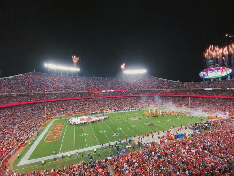 A football stadium filled with spectators, a football field, and a large scoreboard. 2