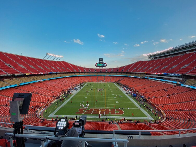A football stadium with red seats, a football field, and a scoreboard. 4