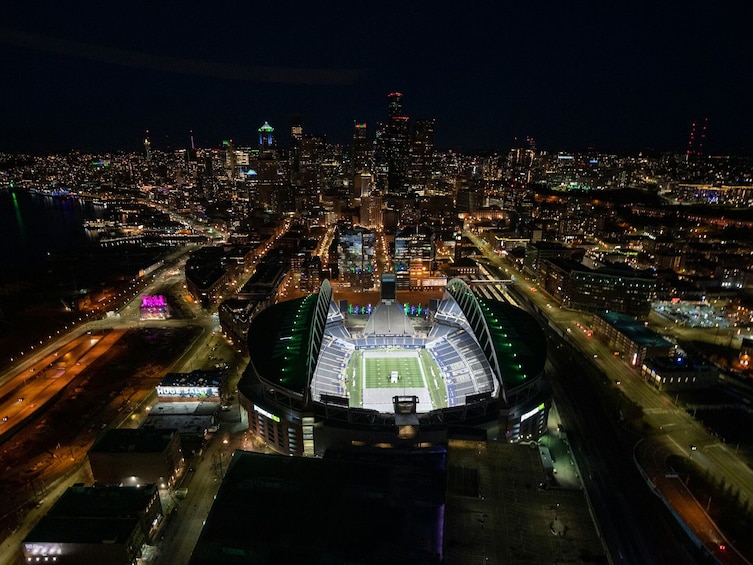 Vista aérea nocturna de un estadio rodeado por un paisaje urbano con edificios iluminados. 2