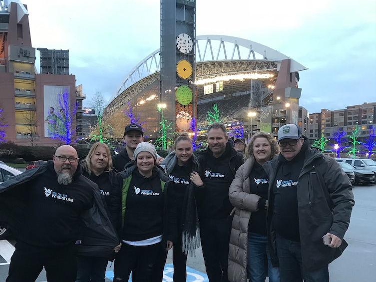 Un grupo de personas frente a un estadio con árboles iluminados y un reloj grande. 4