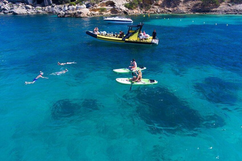 A clear blue sea with people swimming and paddleboarding. 5