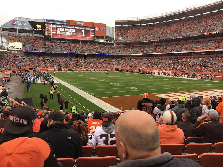 A football stadium with spectators, a scoreboard, and a field. 1