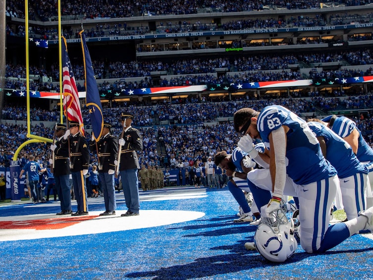 A football field with players, a flag, and a crowd in a stadium. 3