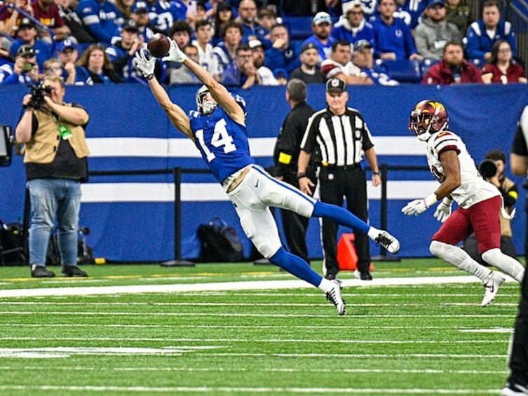 A football player in blue and white uniform leaping to catch a ball. 2