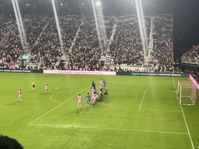 A soccer stadium filled with spectators, a soccer match in progress, and a goalpost. 5