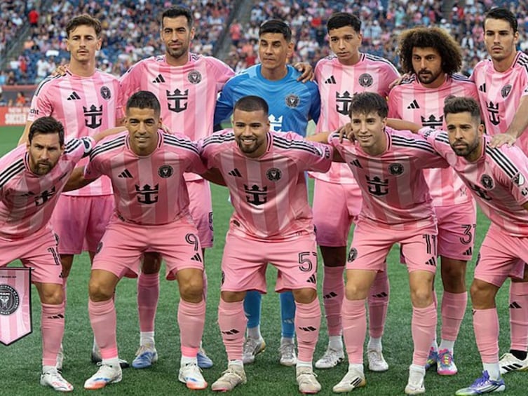 A group of soccer players in pink jerseys posing for a team photo. 2