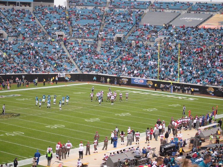 A football stadium with players on the field and spectators in the stands. 3