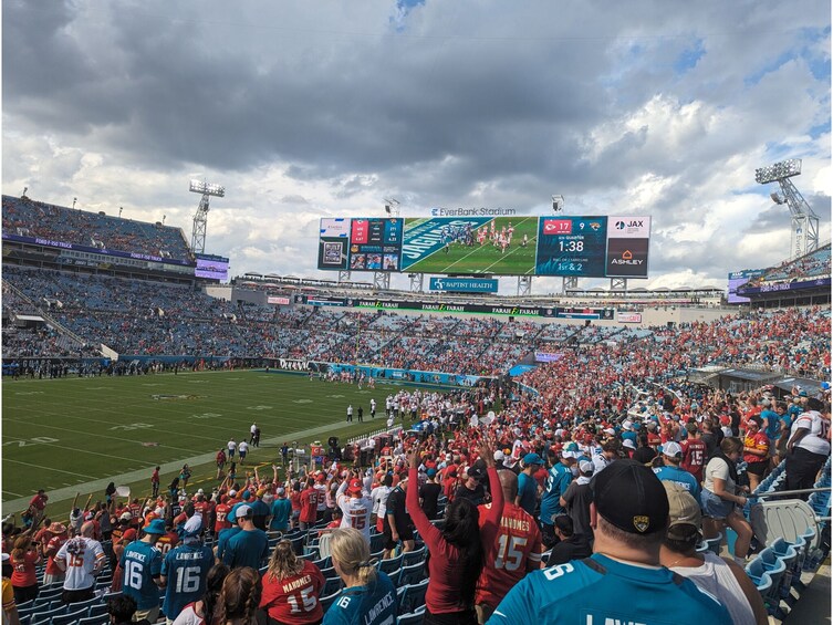 A football stadium filled with spectators, a scoreboard, and advertisements. 5