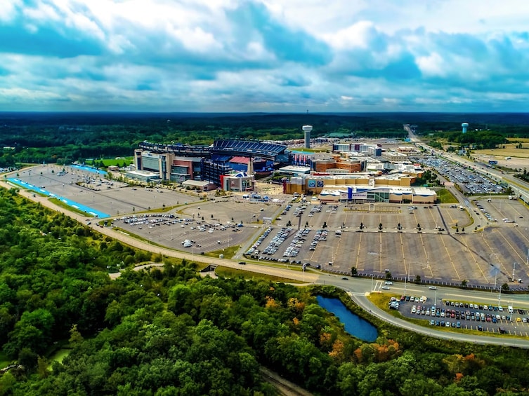 An aerial view of a large stadium complex with parking lots and surrounding greenery. 3
