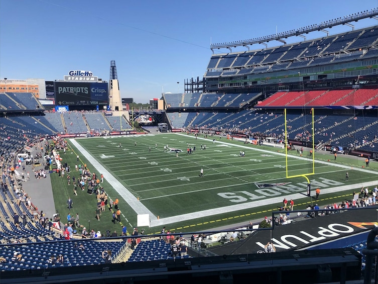A football stadium with empty stands, a football field, and a Gillette sign. 5