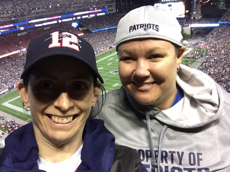 Two people wearing sports caps with a stadium in the background. 2