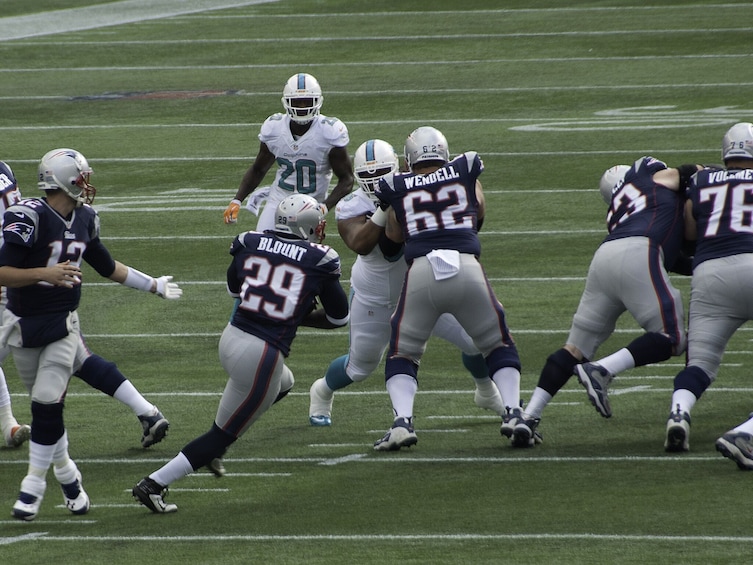 A football game with players in white and navy uniforms on a field. 4