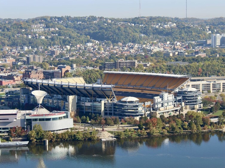 Een modern stadion met een groot dak, omringd door een stadsgezicht en een waterpartij. 4